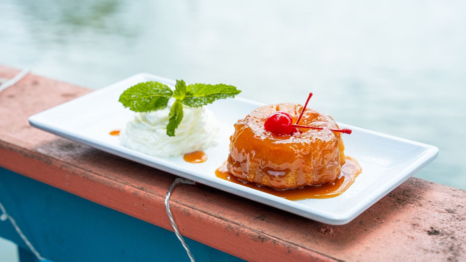Dessert with whipped cream and mint on the deck rail over the water